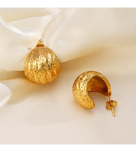 Vue détaillée des boucles d'oreilles dorées avec texture irrégulière sur soie beige