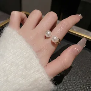 Elegant adjustable gold ring with two white pearls on hand against a cozy white cuff