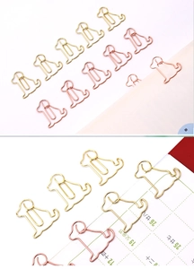 Detail of dog-shaped metal paper clips in gold and rose gold finishes for stationery