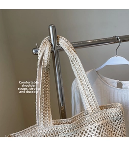 Close-up of beige woven straw tote bag featuring intricate openwork texture and sturdy strap
