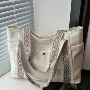 Dettaglio della borsa tote in tela bianco sporco con ampia tracolla geometrica