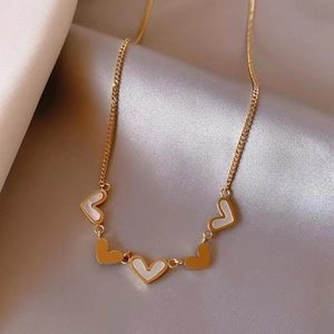 Detailed macro view of heart pendants on golden titanium steel chain with white shell inlay
