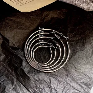 Set of five silver minimalist hoop earrings in sizes 3cm to 7cm on dark background