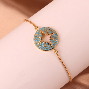 Close-up of gold-plated bracelet with star motif pendant and turquoise bead accents