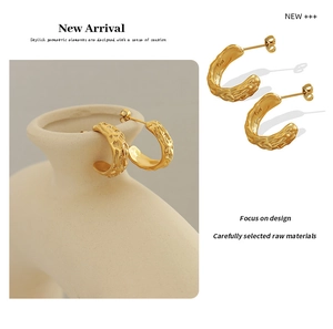 Close-up of gold C-shaped earrings with textured lava finish and stud details