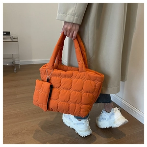 Detail of bright orange quilted tote bag set with matching coin purse and square stitching