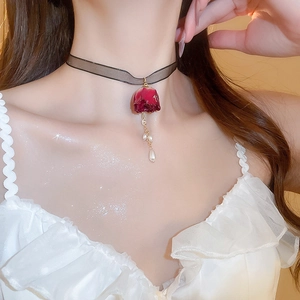 Detail eines Vintage-Spitzenchokers mit rotem Rosenanhänger und Perlenfransen am Hals