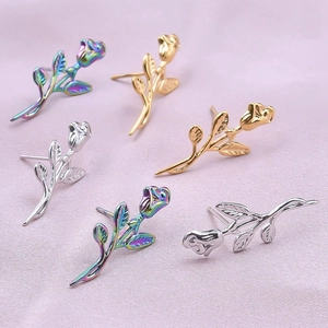 Dettaglio macro di orecchini a forma di rosa in finiture arcobaleno, oro e argento