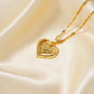 Detail of gold double heart pendant necklace with pink rhinestones on silk background