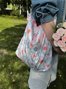 Floral print cotton tote bag shown in outdoor setting with a lady on green grass