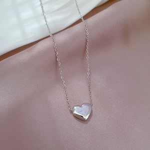 Vue détaillée d'un pendentif cœur poli posé sur un élégant tissu en soie rose doux