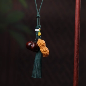 Macro detail of hand-carved sandalwood peanut and persimmon pendants with silk tassels