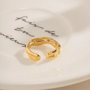 Detail of 18k gold plated snake ring with irregular lava texture on a white plate