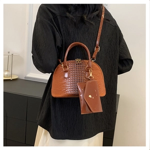Brown crocodile pattern shell bag with matching envelope pouch on a female model