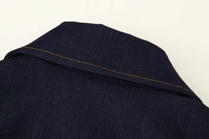 Détail d'un col en denim bleu foncé avec des surpiqûres orange et texture du tissu