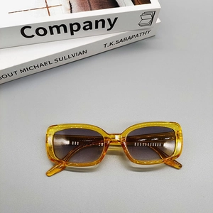 Detail view of retro amber oval sunglasses with gradient lenses resting on a stack of books