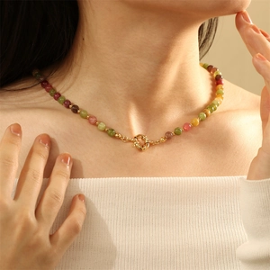 Close-up of a colorful beaded necklace with a central gold metal ring fastener on a neck