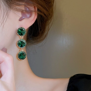 Détail de boucles d'oreilles pendantes en cristal vert avec monture dorée chic