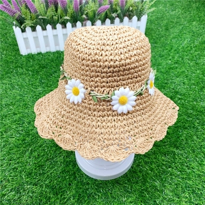 Detail of hand-woven straw sun hat with floral daisy trim and wavy brim edges