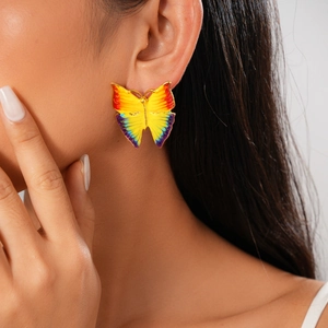 Detail of butterfly earrings with colorful gradient enamel wings on professional model