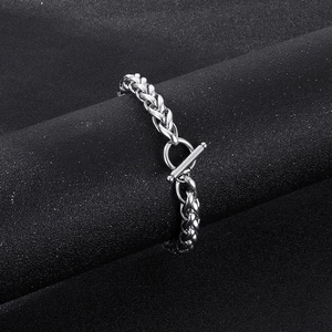 Detail view of a silver stainless steel chain with a toggle clasp on dark textured display