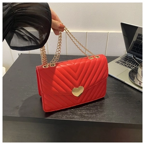 Dettaglio borsa trapuntata rossa con chiusura dorata a forma di cuore e tracolla a catena