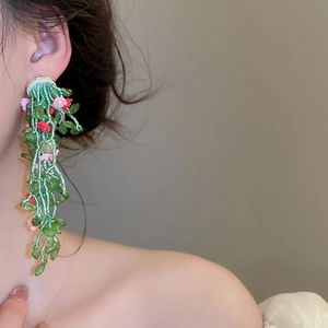 Primer plano de pendientes de borla con flores de cuentas hechos a mano en modelo asiática
