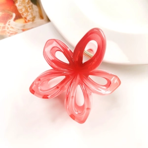 Detailed close-up of a translucent red flower claw clip with hollow petals and gold spring