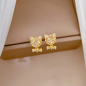 Detail of cat-shaped gold earrings with sparkling zircon crystals and a bow pendant charm