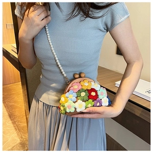 Detail of crochet floral shell bag with wooden frame and elegant pearl chain strap