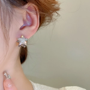 Close-up of minimalist silver star stud earrings with zircon inlay worn by a female model