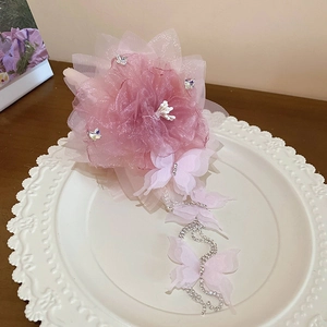 Dettaglio molletta per capelli con fiore in rete rosa, nappe a farfalla e strass