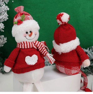 Detail of Christmas plush gnome featuring heart patterns, striped scarf and carrot nose