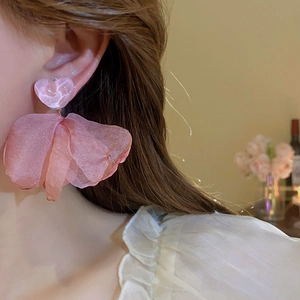 Close-up of pink heart stud earrings with layered mesh flower petals on model