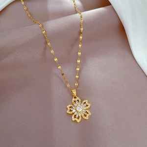 Gros plan d'un collier en titane doré avec pendentif fleur serti de zircons cubiques