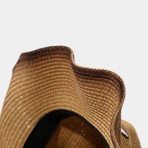 Detail of hand-woven paper straw texture and refined dark piping on a cowboy hat brim