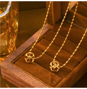 Detail shot of hollow cube pendants on gold chains inside a wooden jewelry box