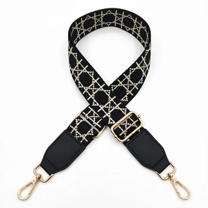 Detail of adjustable wide shoulder strap with beige geometric embroidery and gold hooks