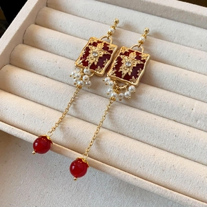 Dettaglio di orecchini a fiocco vintage con perle rosse in un portagioie