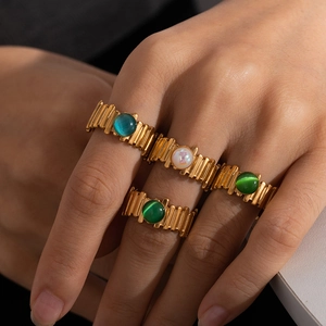 Close-up of four vintage gold rings set with green and white opal stones on hand