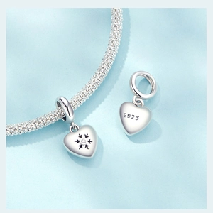 Macro view of S925 sterling silver heart charm with snowflake engraving and small crystals