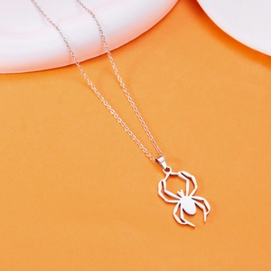 Detail shot of a silver stainless steel spider pendant on an orange festive background