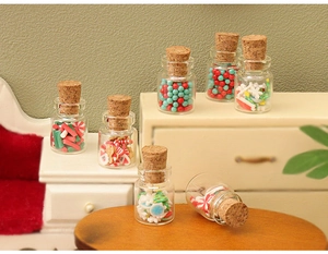 Miniature glass jars with cork stoppers filled with colorful Christmas candies and gingerbread