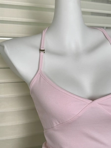 Dettaglio di canotta rosa con fibbie metalliche regolabili e scollo a V con pieghe