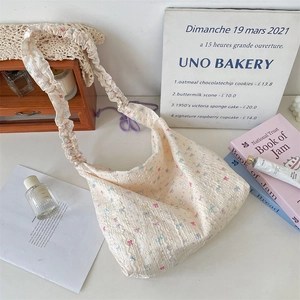 Détail du sac sous les aisselles en toile crème avec motifs nœuds et bandoulière plissée