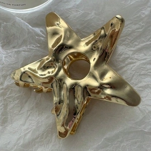 Minimalist gold hollow star metal hair claw clip with a glossy finish on white paper