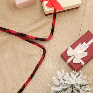 Detail of linen Christmas tree skirt with red buffalo plaid edge on wooden floor