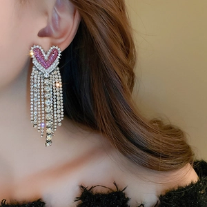 Detailed close-up of a heart-shaped earring with pink crystals and long sparkling tassels