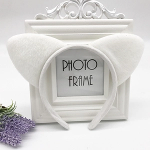 Close-up of white plush cat ear headband displayed on a vintage white photo frame
