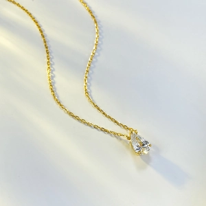 Detailed view of a gold pear-shaped drop pendant with sparkling clear cubic zirconia